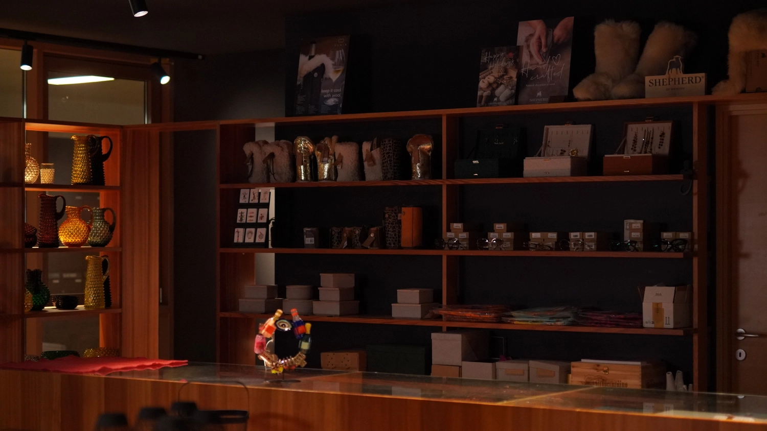 Sipho Studio - Drone visuel - Schwach beleuchteter Ladeninnenraum mit Holzregalen voller Waren hinter einer Glastheke.